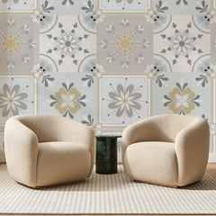 Papier peint panoramique Carreaux Fleuris Gris et Or, posé sur toute la paroi d'un salon, derrière deux fauteuils en bouclette crème et un guéridon en marbre vert
