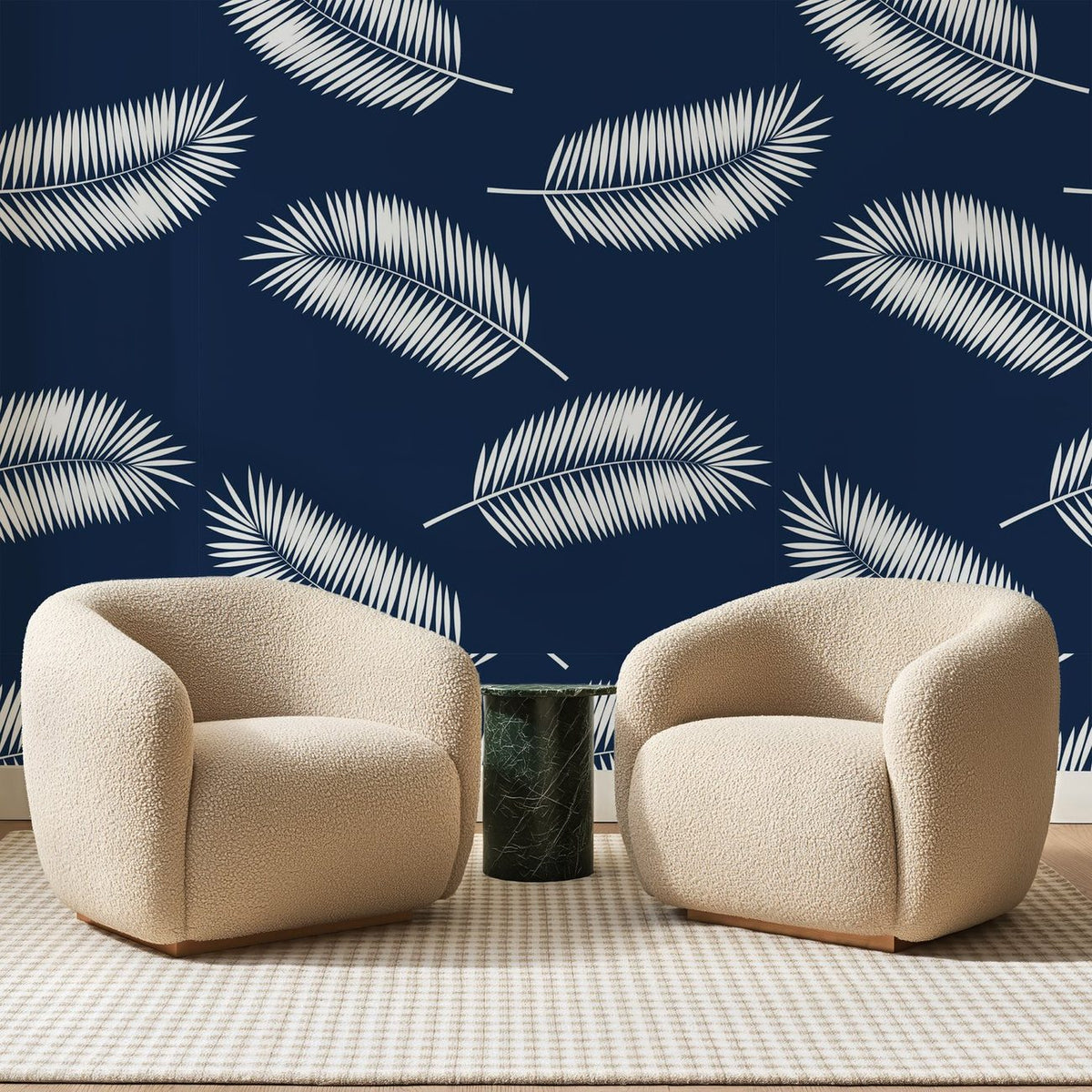 Papier peint panoramique Palmes Blanches sur Bleu Marine, posé sur toute la paroi d'un salon, derrière deux fauteuils en bouclette crème et un guéridon en marbre vert