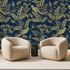 Papier peint panoramique Perruches d'Or sur Bleu Nuit, posé sur toute la paroi d'un salon, derrière deux fauteuils en bouclette crème et un guéridon en marbre vert
