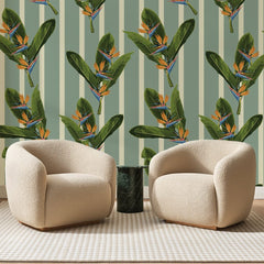 Papier peint panoramique Strelitzias sur Rayures Sauge, posé sur toute la paroi d'un salon, derrière deux fauteuils en bouclette crème et un guéridon en marbre vert.