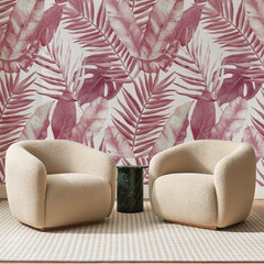 Papier peint panoramique Palmes Tropicales Rose Aquarelle, posé sur toute la paroi d'un salon, derrière deux fauteuils en bouclette crème et un guéridon en marbre vert.
