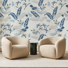 Papier peint panoramique Oiseaux Bleus sur Fond Blanc, posé sur toute la paroi d'un salon, derrière deux fauteuils en bouclette crème et un guéridon en marbre vert