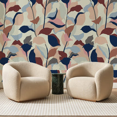 Papier peint panoramique Feuillage Marine et Vieux Rose, posé sur toute la paroi d'un salon, derrière deux fauteuils en bouclette crème et un guéridon en marbre vert