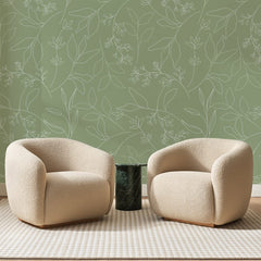 Papier peint panoramique Rameaux au Trait Vert Sauge, posé sur toute la paroi d'un salon, derrière deux fauteuils en bouclette crème et un guéridon en marbre vert.
