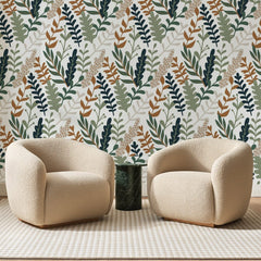 Papier peint panoramique Fougères Mêlées Vert et Rouille, posé sur toute la paroi d'un salon, derrière deux fauteuils en bouclette crème et un guéridon en marbre vert