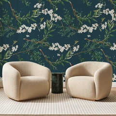 Papier peint panoramique Branches Fleuries Bleu Canard, posé sur toute la paroi d'un salon, derrière deux fauteuils en bouclette crème et un guéridon en marbre vert