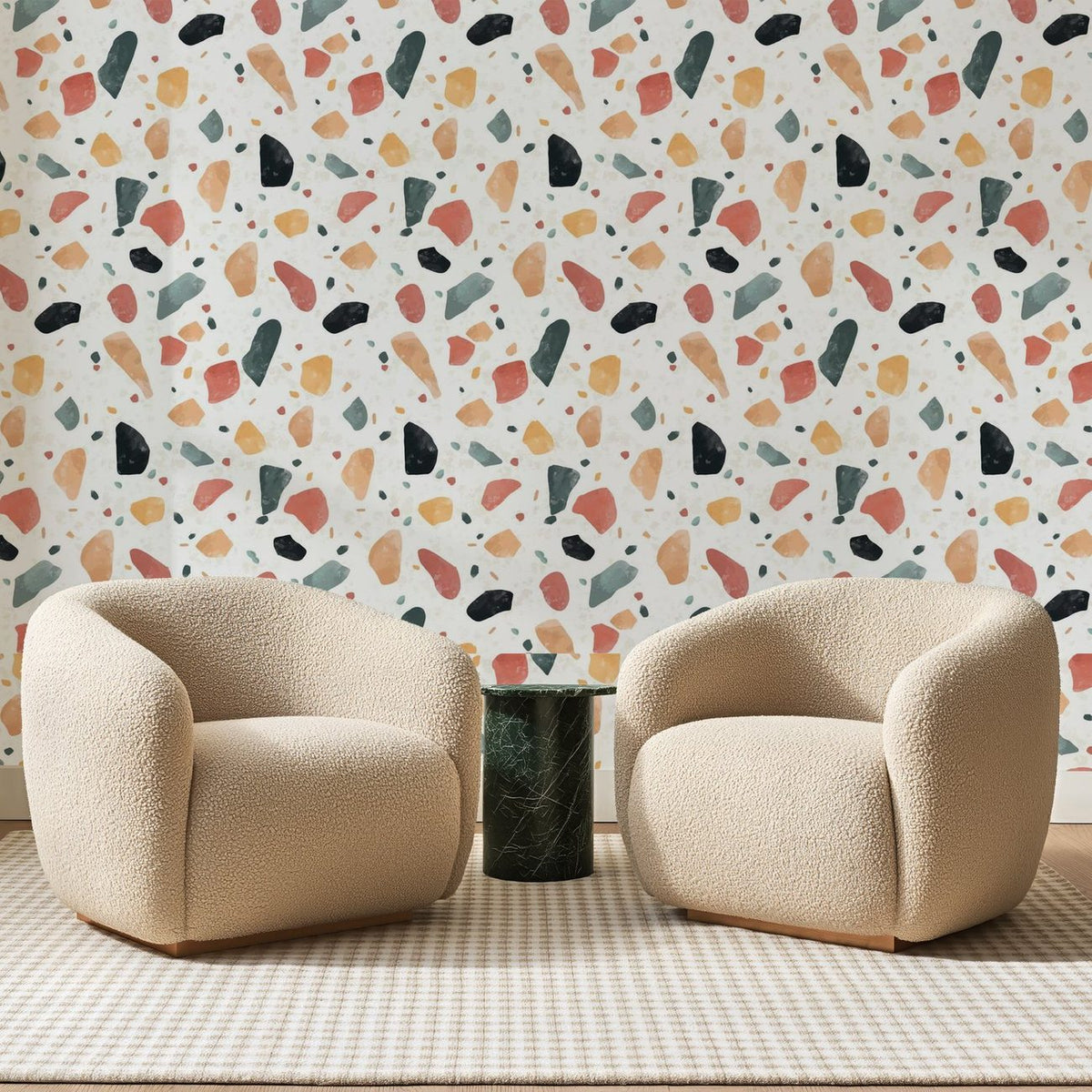 Papier peint panoramique Granito Peint Corail Et Sauge, posé sur toute la paroi d'un salon, derrière deux fauteuils en bouclette crème et un guéridon en marbre vert