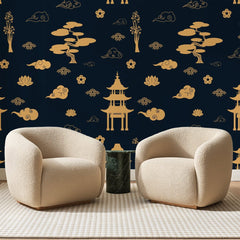 Papier peint panoramique Pagodes Dorées sur Bleu Nuit, posé sur toute la paroi d'un salon, derrière deux fauteuils en bouclette crème et un guéridon en marbre vert.