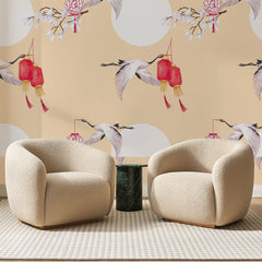 Papier peint panoramique Grues et Lanternes Abricot, posé sur toute la paroi d'un salon, derrière deux fauteuils en bouclette crème et un guéridon en marbre vert