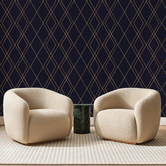 Papier peint panoramique Résille de Diamants Prune, posé sur toute la paroi d'un salon, derrière deux fauteuils en bouclette crème et un guéridon en marbre vert