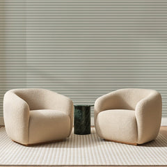 Papier peint panoramique Fines Rayures Vert Sauge, posé sur toute la paroi d'un salon, derrière deux fauteuils en bouclette crème et un guéridon en marbre vert