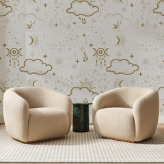 Papier peint panoramique Ciel Bohème Doré, posé sur toute la paroi d'un salon, derrière deux fauteuils en bouclette crème et un guéridon en marbre vert