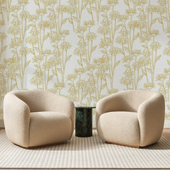 Papier peint panoramique Marguerites au Trait Ocre, posé sur toute la paroi d'un salon, derrière deux fauteuils en bouclette crème et un guéridon en marbre vert
