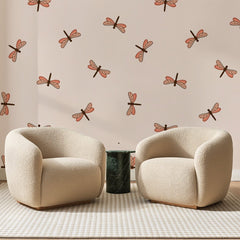 Papier peint panoramique Libellules Corail Sur Rose, posé sur toute la paroi d'un salon, derrière deux fauteuils en bouclette crème et un guéridon en marbre vert