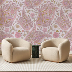 Papier peint panoramique Cachemire Fleuri Rose et Moutarde, posé sur toute la paroi d'un salon, derrière deux fauteuils en bouclette crème et un guéridon en marbre vert