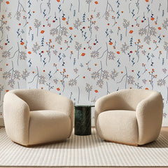 Papier peint panoramique Brindilles Corail sur Blanc, posé sur toute la paroi d'un salon, derrière deux fauteuils en bouclette crème et un guéridon en marbre vert