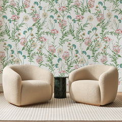 Papier peint panoramique Fleurs des Champs Rose Tendre, posé sur toute la paroi d'un salon, derrière deux fauteuils en bouclette crème et un guéridon en marbre vert