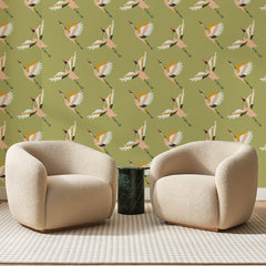 Papier peint panoramique Vol de Grues Kaki, posé sur toute la paroi d'un salon, derrière deux fauteuils en bouclette crème et un guéridon en marbre vert