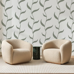 Papier peint panoramique Lianes Sauge sur Blanc, posé sur toute la paroi d'un salon, derrière deux fauteuils en bouclette crème et un guéridon en marbre vert