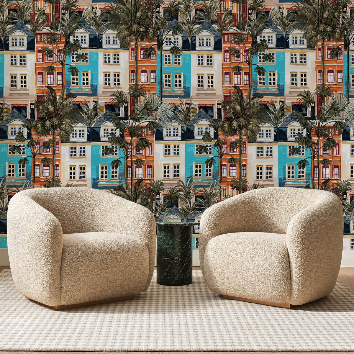Papier peint panoramique Façades Méditerranéennes Terracotta, posé sur toute la paroi d'un salon, derrière deux fauteuils en bouclette crème et un guéridon en marbre vert