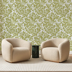 Papier peint panoramique Rinceaux d'Acanthe Olive, posé sur toute la paroi d'un salon, derrière deux fauteuils en bouclette crème et un guéridon en marbre vert