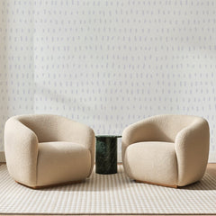 Papier peint panoramique Petits Traits Gris Lavande, posé sur toute la paroi d'un salon, derrière deux fauteuils en bouclette crème et un guéridon en marbre vert