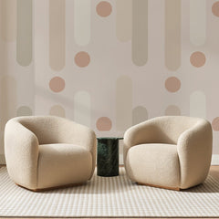 Papier peint panoramique Colonnes et Pois Beige Rosé, posé sur toute la paroi d'un salon, derrière deux fauteuils en bouclette crème et un guéridon en marbre vert