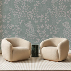 Papier peint panoramique Herbier Rose sur Vert Jade, posé sur toute la paroi d'un salon, derrière deux fauteuils en bouclette crème et un guéridon en marbre vert