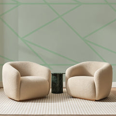 Papier peint panoramique Lignes Brisées Vert Amande, posé sur toute la paroi d'un salon, derrière deux fauteuils en bouclette crème et un guéridon en marbre vert