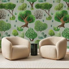 Papier peint panoramique Petite Forêt Vert Sauge, posé sur toute la paroi d'un salon, derrière deux fauteuils en bouclette crème et un guéridon en marbre vert