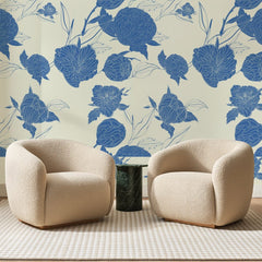 Papier peint panoramique Pivoines Bleues sur Crème, posé sur toute la paroi d'un salon, derrière deux fauteuils en bouclette crème et un guéridon en marbre vert