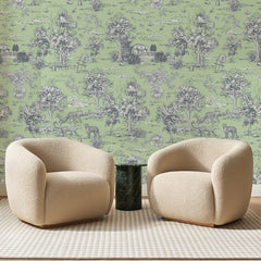 Papier peint panoramique Léopards de Jouy Vert Tilleul, posé sur toute la paroi d'un salon, derrière deux fauteuils en bouclette crème et un guéridon en marbre vert