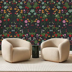 Papier peint panoramique Fraises Des Bois Anthracite, posé sur toute la paroi d'un salon, derrière deux fauteuils en bouclette crème et un guéridon en marbre vert