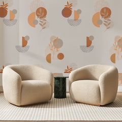 Papier peint panoramique Cercles et Rameaux Terracotta, posé sur toute la paroi d'un salon, derrière deux fauteuils en bouclette crème et un guéridon en marbre vert