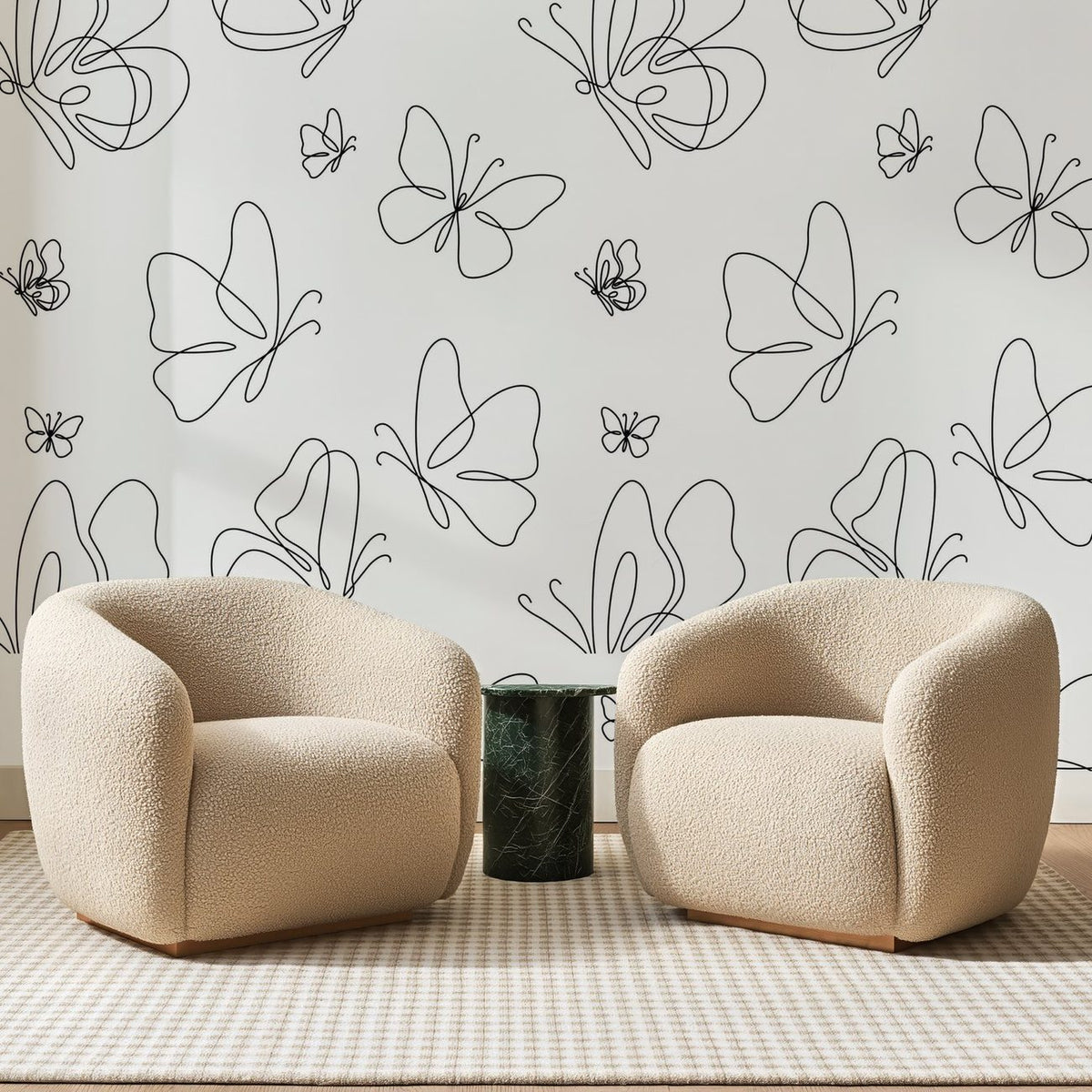 Papier peint panoramique Papillons au Trait Noir, posé sur toute la paroi d'un salon, derrière deux fauteuils en bouclette crème et un guéridon en marbre vert