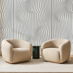 Papier peint panoramique Lignes Ondulées Encre Noire, posé sur toute la paroi d'un salon, derrière deux fauteuils en bouclette crème et un guéridon en marbre vert