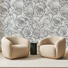 Papier peint panoramique Roses au Trait Anthracite, posé sur toute la paroi d'un salon, derrière deux fauteuils en bouclette crème et un guéridon en marbre vert