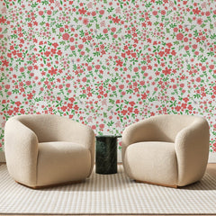 Papier peint panoramique Semis Fleuri Corail Et Vert, posé sur toute la paroi d'un salon, derrière deux fauteuils en bouclette crème et un guéridon en marbre vert
