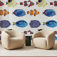 Papier peint panoramique Poissons Tropicaux Bleu Roi, posé sur toute la paroi d'un salon, derrière deux fauteuils en bouclette crème et un guéridon en marbre vert