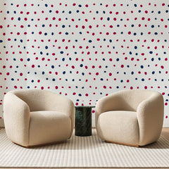 Papier peint panoramique Pois Peints Framboise et Marine, posé sur toute la paroi d'un salon, derrière deux fauteuils en bouclette crème et un guéridon en marbre vert