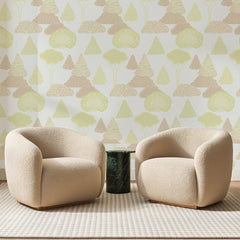 Papier peint panoramique Forêt Naïve Vert Anis, posé sur toute la paroi d'un salon, derrière deux fauteuils en bouclette crème et un guéridon en marbre vert