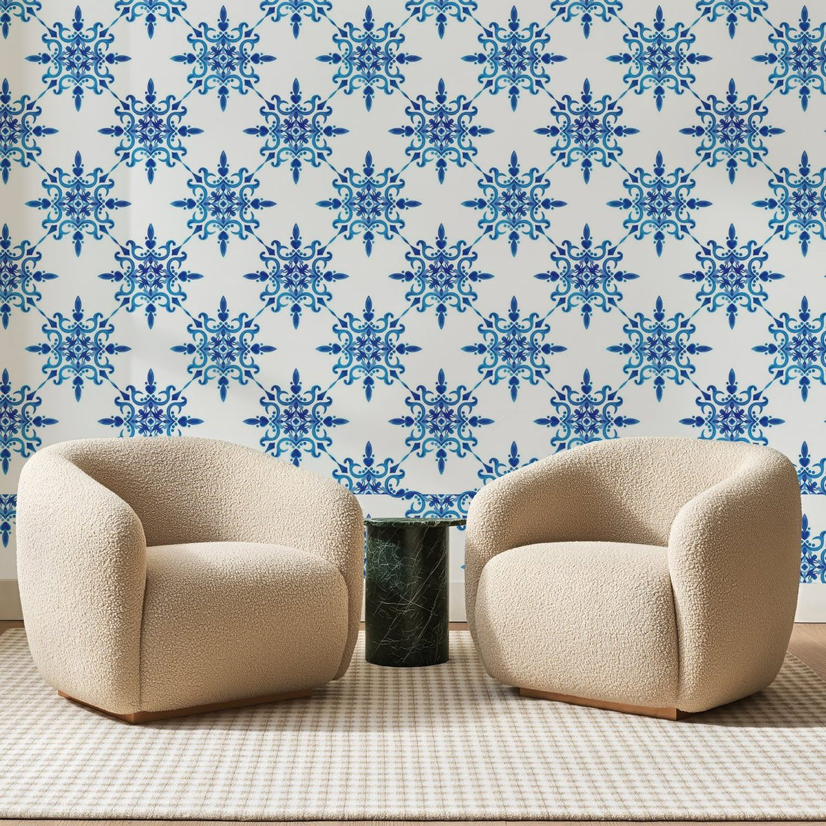 Papier peint panoramique Petites Rosaces Bleu Indigo, posé sur toute la paroi d'un salon, derrière deux fauteuils en bouclette crème et un guéridon en marbre vert