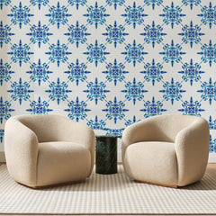 Papier peint panoramique Petites Rosaces Bleu Indigo, posé sur toute la paroi d'un salon, derrière deux fauteuils en bouclette crème et un guéridon en marbre vert