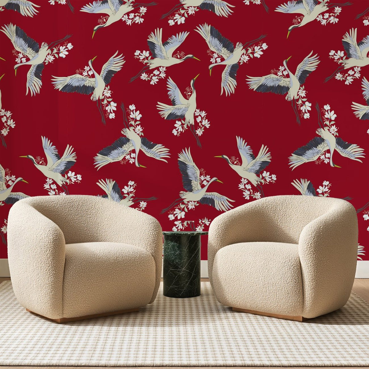 Papier peint panoramique Grues Japonaises Rouge Carmin, posé sur toute la paroi d'un salon, derrière deux fauteuils en bouclette crème et un guéridon en marbre vert