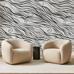 Papier peint panoramique Mèches d'Encre Noire, posé sur toute la paroi d'un salon, derrière deux fauteuils en bouclette crème et un guéridon en marbre vert