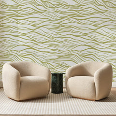 Papier peint panoramique Houle au Trait Vert Olive, posé sur toute la paroi d'un salon, derrière deux fauteuils en bouclette crème et un guéridon en marbre vert