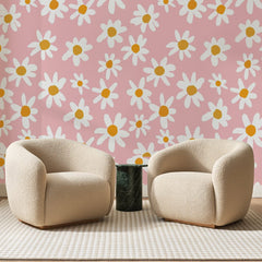 Papier peint panoramique Grandes Marguerites Rose Poudré, posé sur toute la paroi d'un salon, derrière deux fauteuils en bouclette crème et un guéridon en marbre vert
