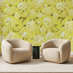 Papier peint panoramique Hortensias Jaune Citron, posé sur toute la paroi d'un salon, derrière deux fauteuils en bouclette crème et un guéridon en marbre vert