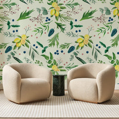 Papier peint panoramique Herbier Fleuri Ivoire, posé sur toute la paroi d'un salon, derrière deux fauteuils en bouclette crème et un guéridon en marbre vert
