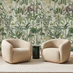 Papier peint panoramique Jardin aux Éléphants Vert Pâle, posé sur toute la paroi d'un salon, derrière deux fauteuils en bouclette crème et un guéridon en marbre vert